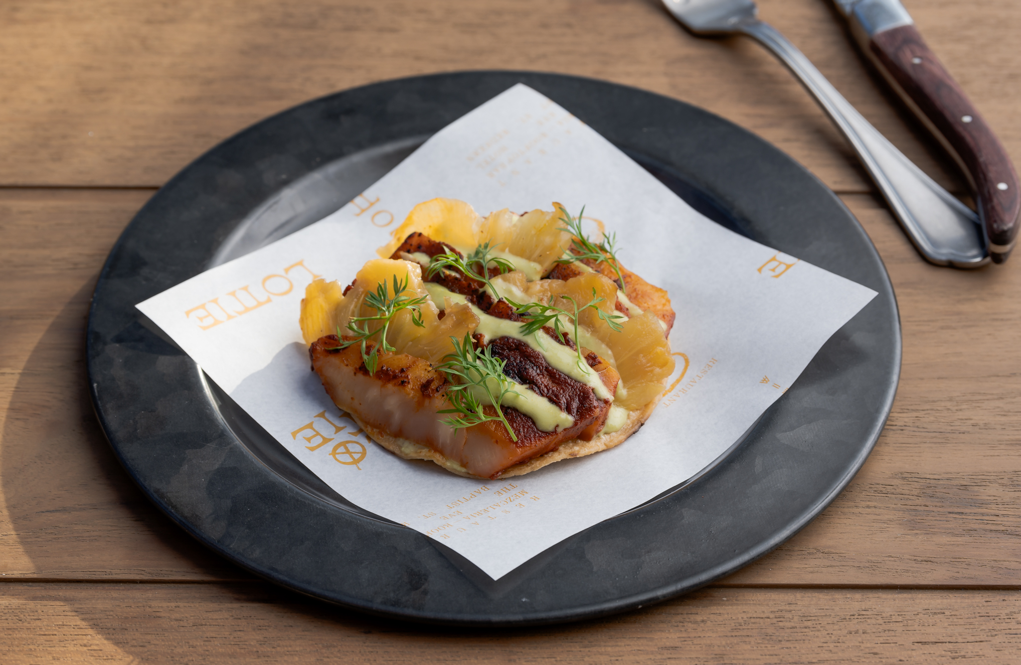 A tostada on a black plate on a table.